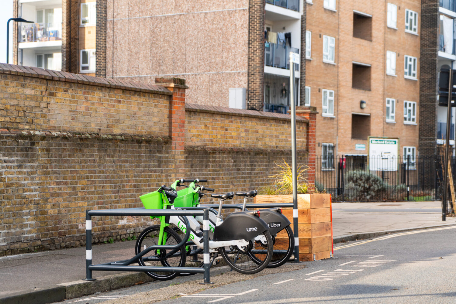 Two Lime bikes at a dockless cycle hangar next to a residential building